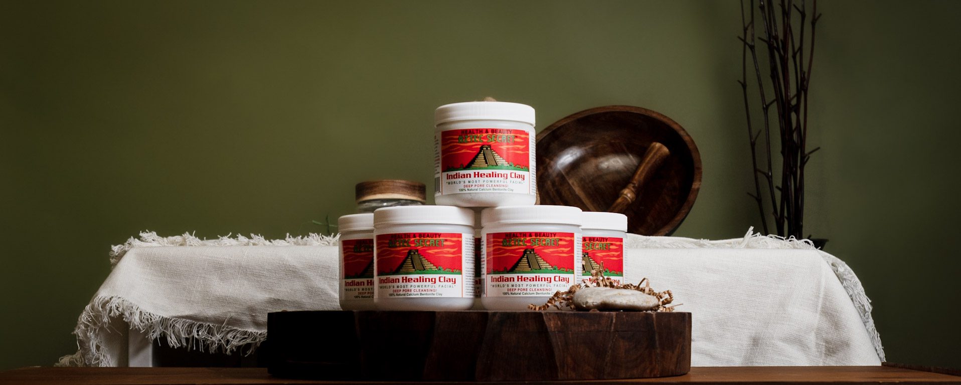 An image showing several jars of Indian Healing Clay on a table with some rustic wooden items.